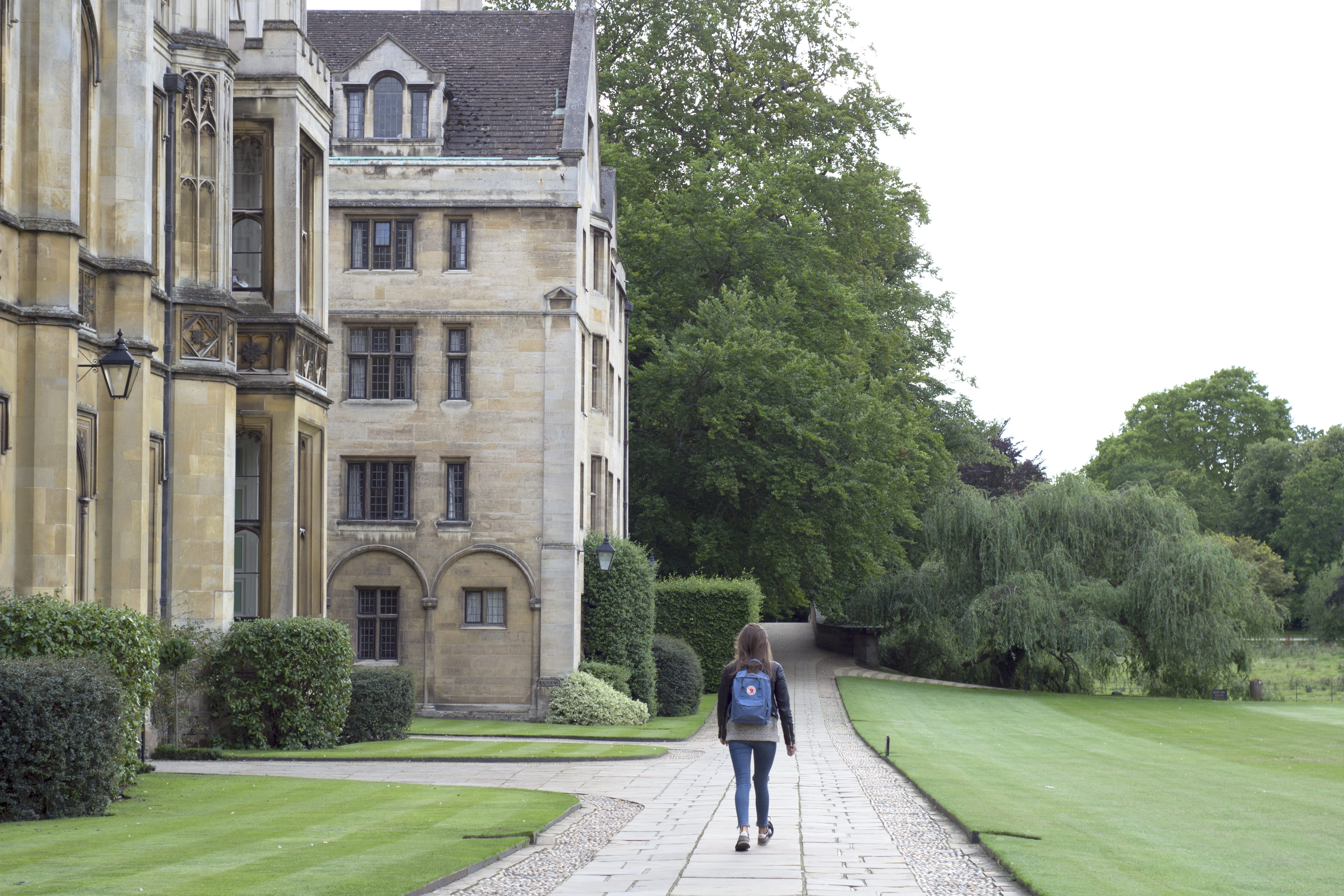 Female student with blue backpack walking around university campus